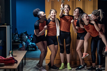 Young female team in euphoria posing with the cup