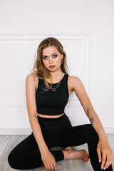 Woman sitting on a wooden floor near a white wall in steals