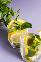 Homemade lemonade with mint in glasses on a grey background. Water with lemon, mint and ice. Health concept