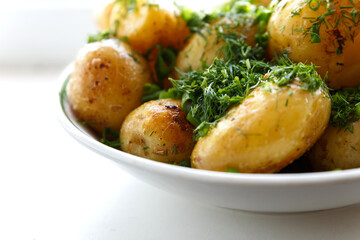 Young round fried potatoes, sprinkled with finely chopped dill. Close-up