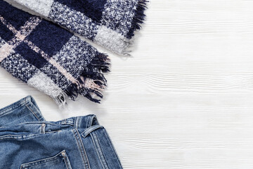 Women's clothing set, warm scarf, blue jeans. Fashion concept with warm stylish clothes. Top view and copy space.