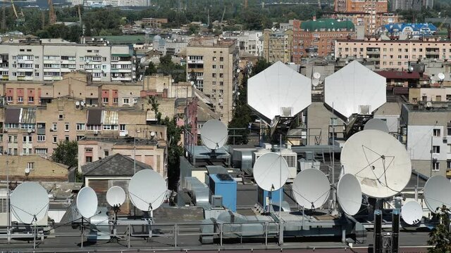 Many satellite dishes on the roof of building