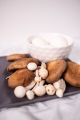 assorted mushrooms on black plate and eggs on white plate on black background for vegan food