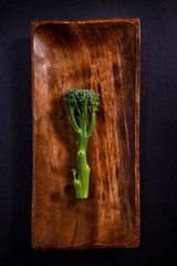 broccoli in wooden plate on black background