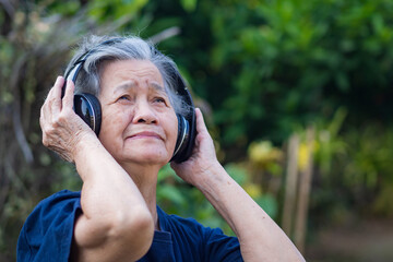 Senior woman listening music from wireless headphone