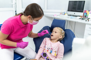 Teeth checkup at dentist's office. Dentist examining girls teeth in the dentists chair.