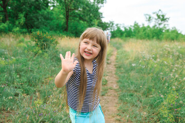 Baby girl waving her hands in the meadow