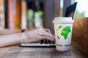 Man working on laptop, reusable cup of coffee