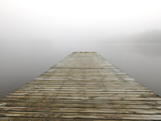 Mystical foggy morning on the lake in autumn. Landscape with a pier against the backdrop of a...