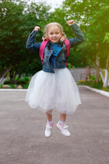 Little schoolgirl happily jumping with a backpack on her shoulders