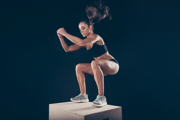 Portrait of her she nice attractive focused sportive strong muscular slim thin slender lady working out standing on wooden box isolated over black background