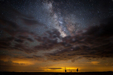The Milky Way stars partially obscured by a layer of clouds in the night sky
