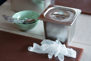 Metal food container and disposable gloves on the kitchen table, close-up.