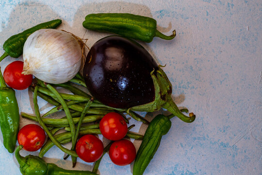 still life con Verduras frescas del huerto sobre mesa de madera con cebollas, zapallitos. tomates, berenjena, habas y pimiento verde.