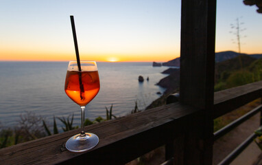 a glass of spritz in front of a beautiful sunset