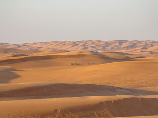 Fototapeta na wymiar Landscape of sand dunes on desert with village in distance