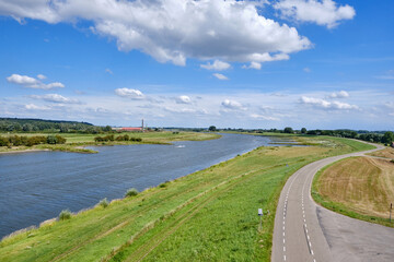 Typical Dutch river landscape with cows, grassland, floodplain, dike with road and the river Rhine with groyne in river bend near Wageningen, Gelderland, the Netherlands