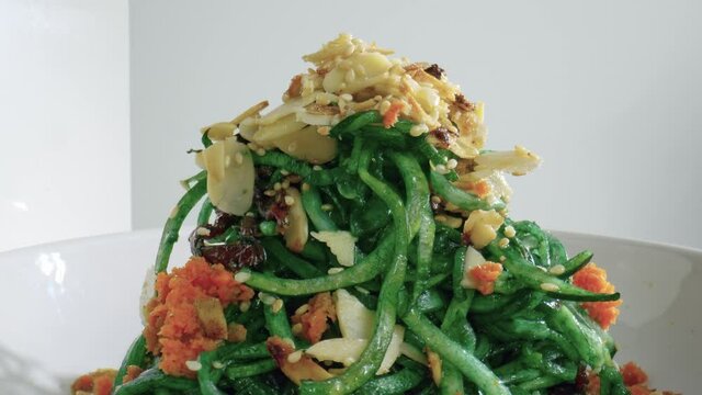 Top view of the rotating white dish with zucchini noodles and almond Restaurant dish side view closeup