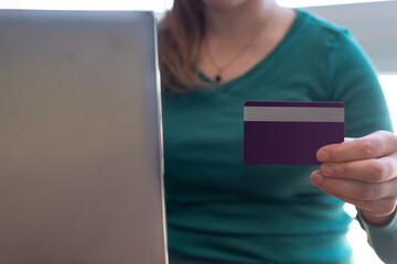 woman holding a credit card in front of a laptop