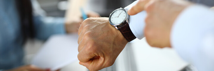 Man in office shows a finger at clock. Improving work efficiency during working hours concept