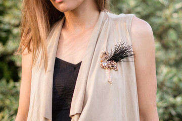 Woman wearing a handmade flamingo brooch made of beads and stones © Yulia