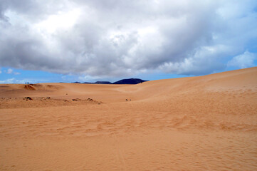 Fototapeta na wymiar huge sand dunes with clouds hanging over them and mountains on the horizon. Corralejo dunas, Fuerteventura, Canary islands