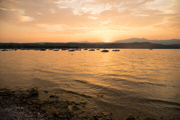 Lake view at sunset with boats in the distance, Manerba del Garda, Italy.