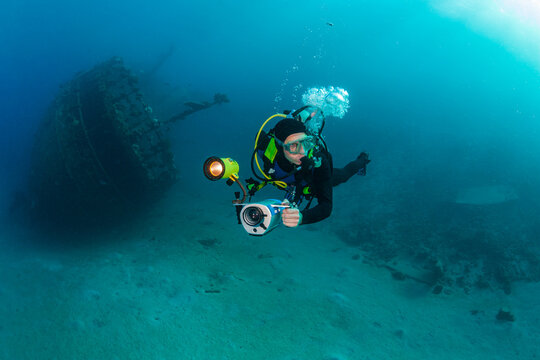 Diver with underwater video camera dives near the wreck, Red Sea.