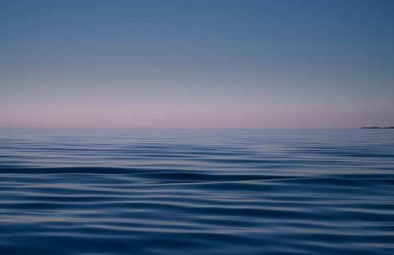 Blue sea and pink sky background. Waves shot at long exposure.