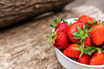 wooden bowl full of fresh strawberries on the brown table