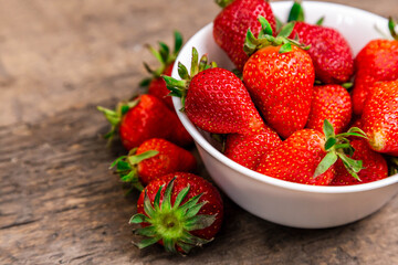 wooden bowl full of fresh strawberries on the brown table