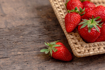 Fresh juicy strawberries in basket. Wicker basket full of freshly picked strawberries on vintage wooden background. Time for eating strawberries.