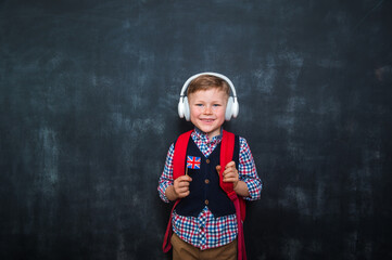 Kid in uniform and headphones holding a flag of United Kingdom and book in hands. Great Britain flag. British flag. Education and learn English. International language school concept.