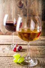 Glasses with wine. Red and white wine in glasses with grape on wooden background copy space