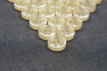 Plastic shiny buttons for clothes on a fabric background. Fashion and clothing. Factory industry.