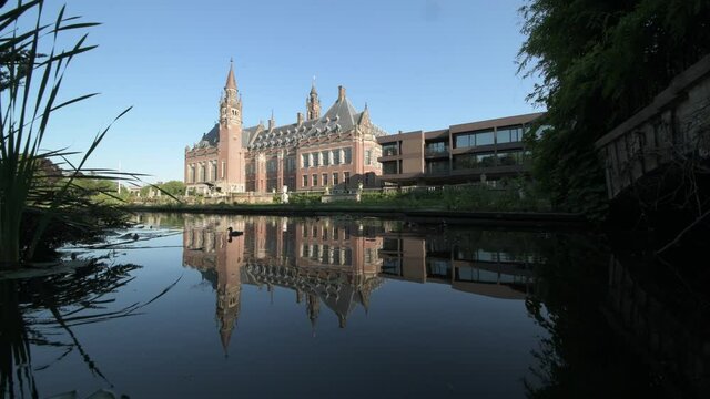Peace Palace, one of the most visited monument in The Hague, reflected on the calm water of the rose garden and its pond, Netherlands