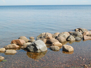 Fototapeta na wymiar Seascape on a summer sunny day: stones near the shore, water