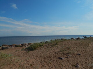 Nice view: sandy seashore, stones, horizon and blue sky