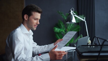 Businessman looking at graphics on document. Freelancer working on laptop