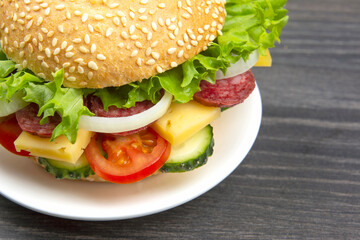 Hamburger with vegetables and sausage. Fast food and breakfast. Calories and diet.