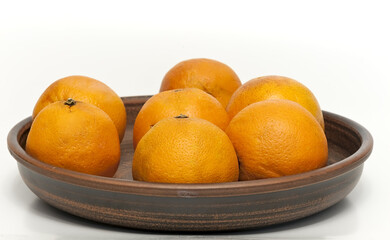 Bunch of oranges on ceramic plate on isolated white background