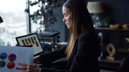 Businesswoman working with papers. Professional looking at reports on document