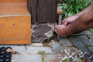 A man repairs an old crumbling concrete post in a country house.