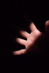 Hand gesture on dark background. Light panned into the hand.