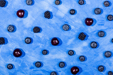 Blueberry, cherry and blackberry pattern on blue background.  Top view