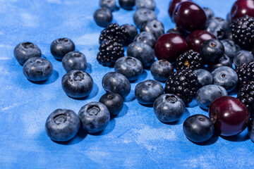 Blueberry, cherry and blackberry on blue background.