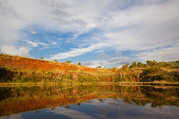 Fototapeta na wymiar Reflexive lake with blue sky, clouds and green vegetation