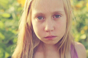 Portrait of cute sad girl in the sunflowers field
