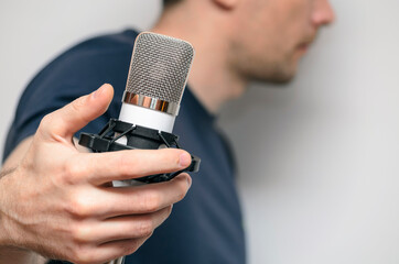 voice recording, a man sings into a condenser microphone