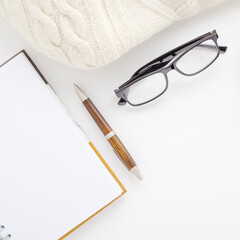 Workspace with pen, notebook, coffee cup, glasses.